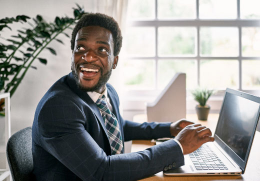 Man smiling while using laptop.