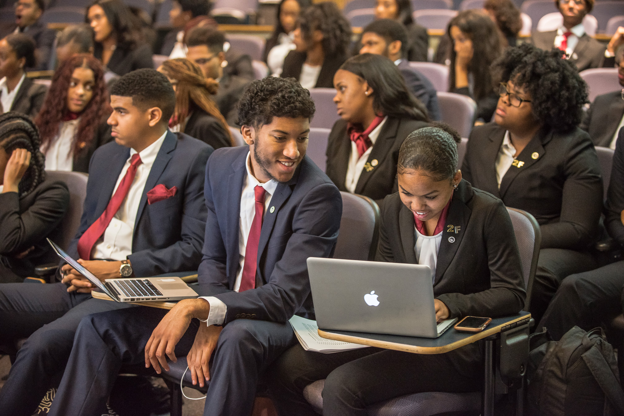 Students in suits sitting in an auditorium.